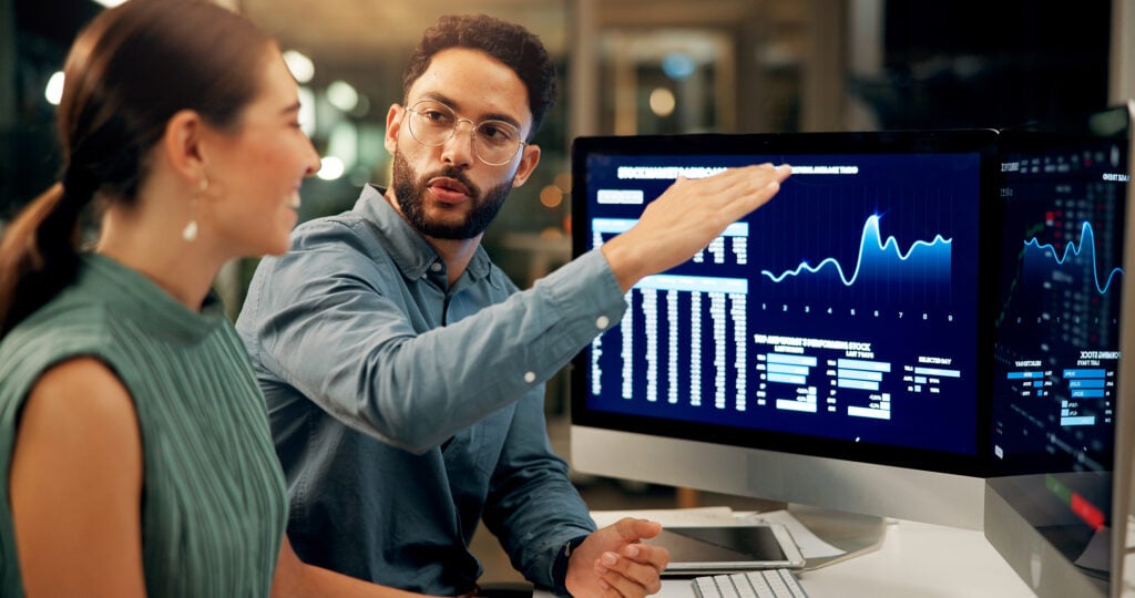 Business people, stock market and night with computer for profit, financial growth or increase at office. Businessman, woman or brokers with tech screen or display for online trading or investment.